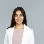 Smiling indian young businesswoman wear white suit looking at camera isolated on grey studio background, happy attractive confident hindu business lady professional head shot close up portrait